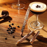 Caffè macchiato with coffee beans and a pipe on a wooden surface